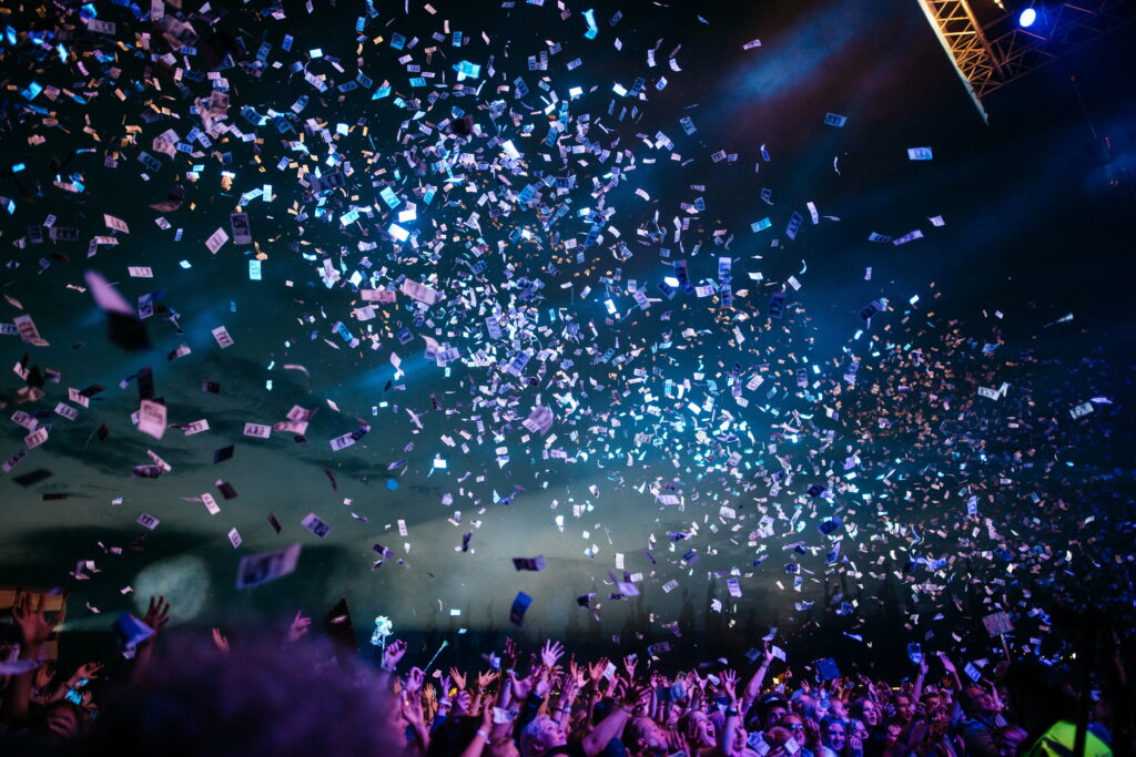 Crowd at concert with blue stage lights and raining paper bills vibrant energetic live music wallpaper