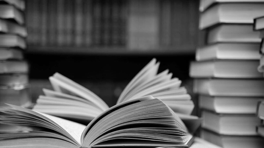 Monochrome Wallpaper: Timeless Book Stack with Dramatic Shadows