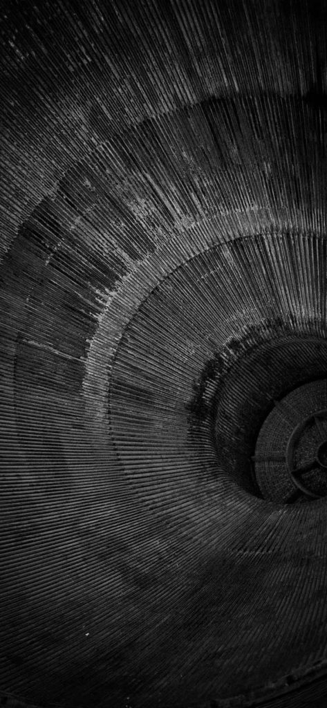 Monochrome iPhone wallpaper of detailed ribbed rocket engine nozzle interior with industrial depth