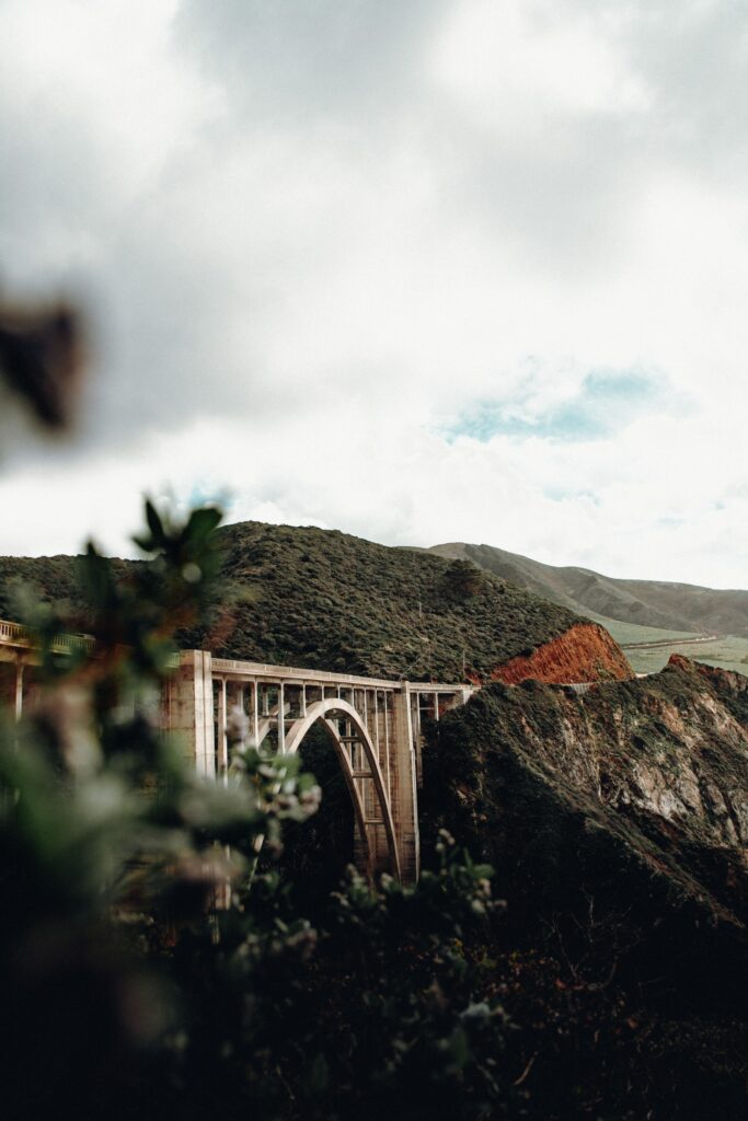 Monterey California iconic bridge with green hills rugged mountains and cloudy sky wallpaper background