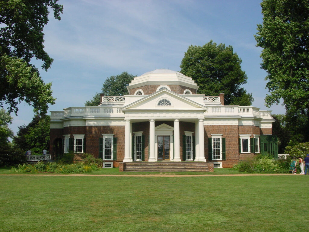 Monticello neoclassical estate with brick facade white columns green trees and blue sky background Wallpaper