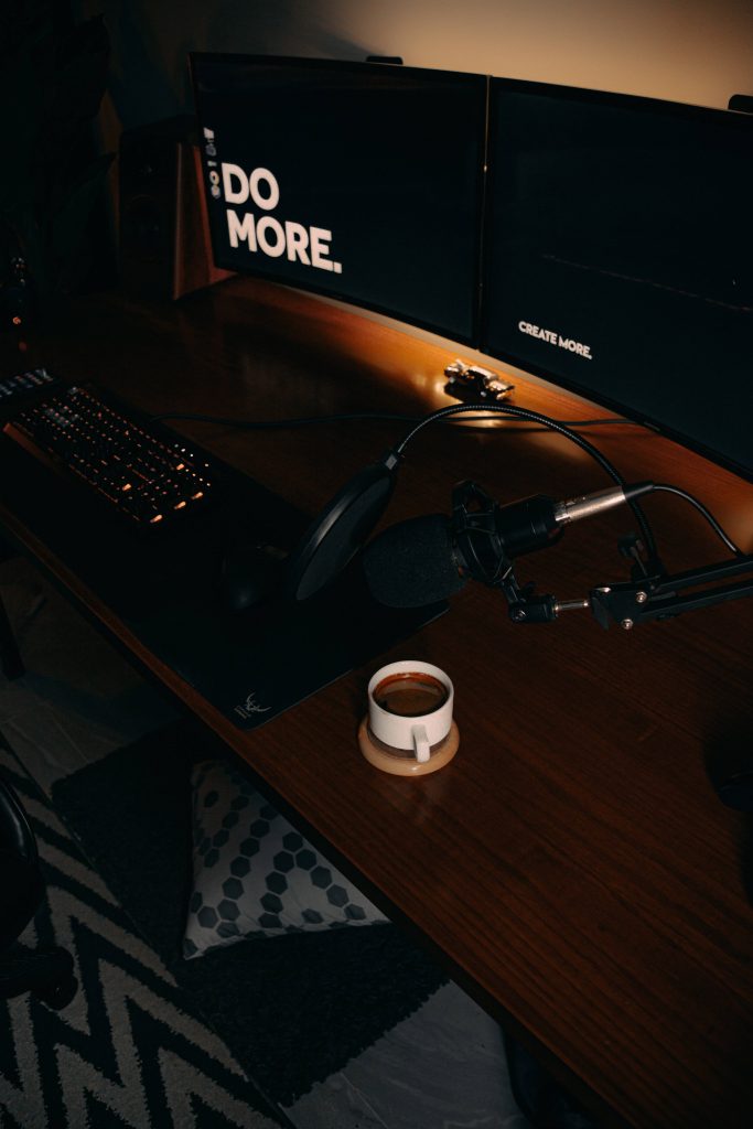 Moody dual monitor desk setup wallpaper with motivational text coffee and microphone for iPhone