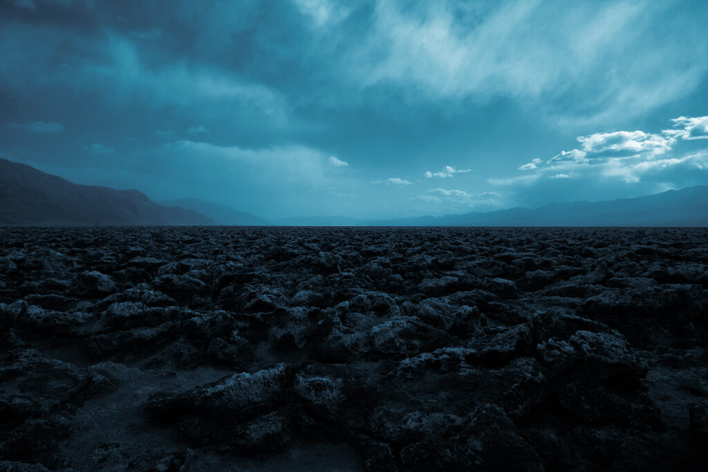 Dramatic desert landscape with rugged stones misty mountains and soft blue foggy sky wallpaper