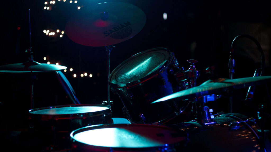 Classic drum set illuminated by blue and violet stage lights with shiny cymbals wallpaper