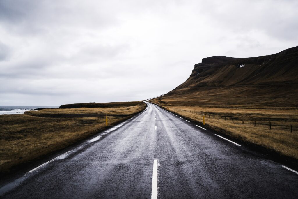 Winding coastal road along rugged cliffs and open fields under a moody cloudy sky wallpaper