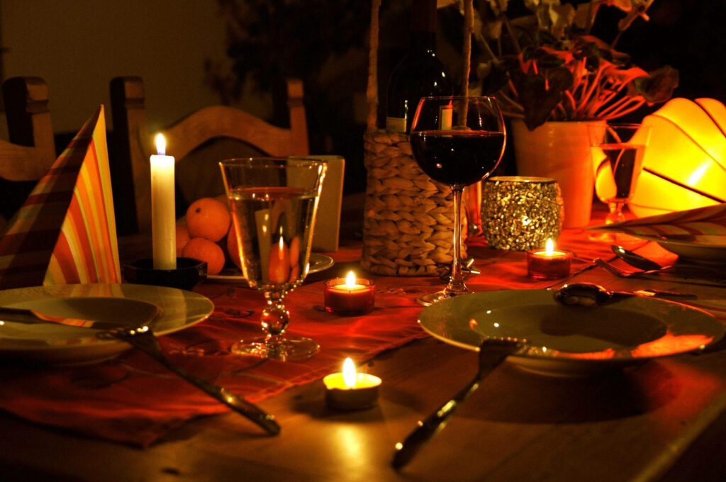 Moody dark dinner table with warm candlelight elegant glassware and romantic cozy setting wallpaper