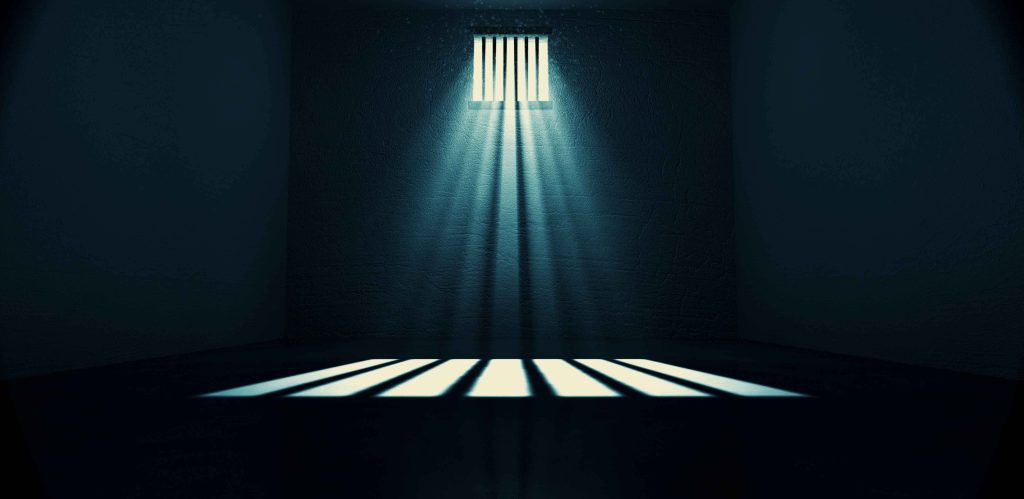 Dark empty jail cell with a single beam of light and sharp shadows digital prison wallpaper
