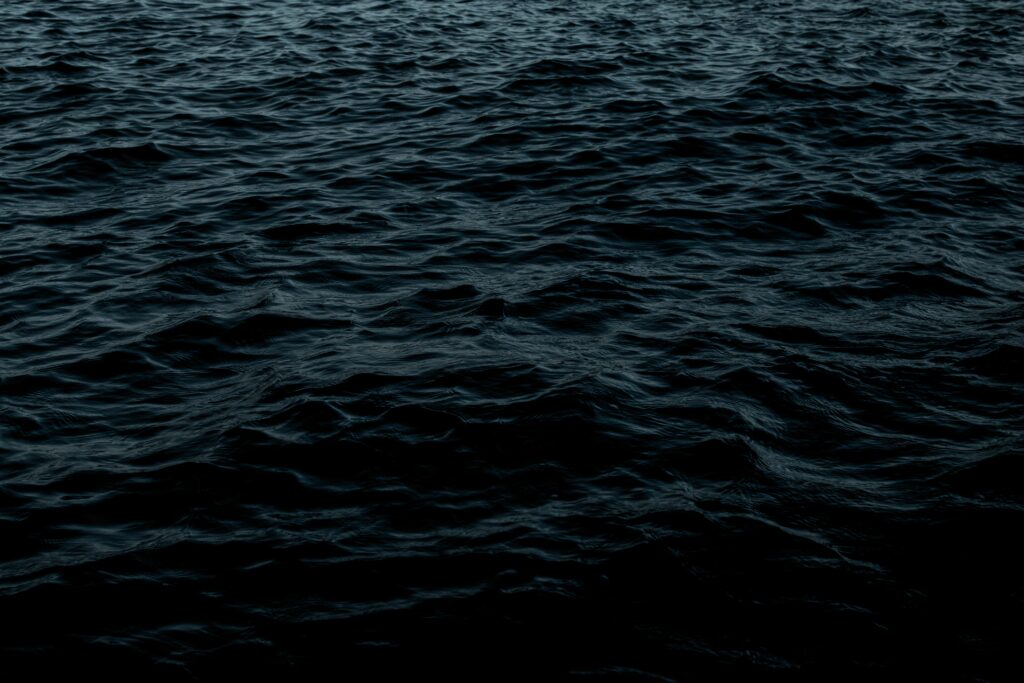 Dark textured water with gentle ripples creating a moody and calming wallpaper background