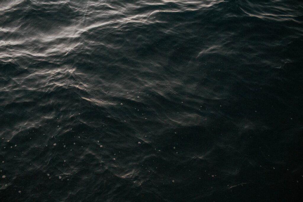 Moody dark water wallpaper with gentle waves and subtle light reflections for calm ambiance
