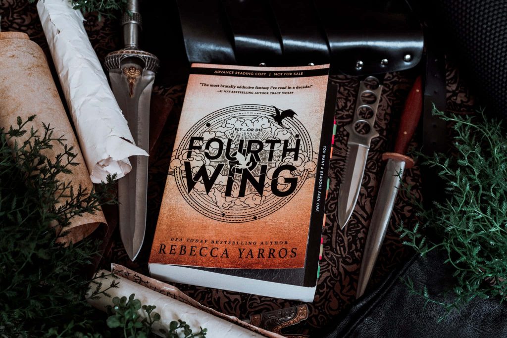 Rustic Fourth Wing book display with daggers scrolls and dark leather moody wallpaper background