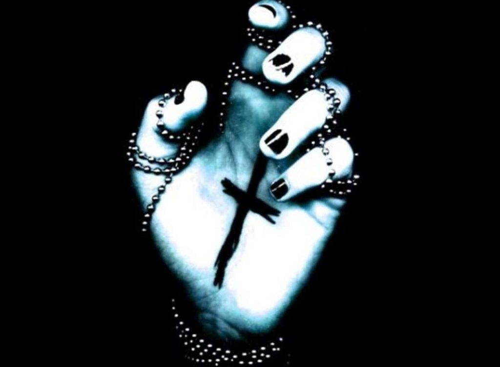 Moody gothic wallpaper close-up of hand clutching beaded rosary and cross on dark background