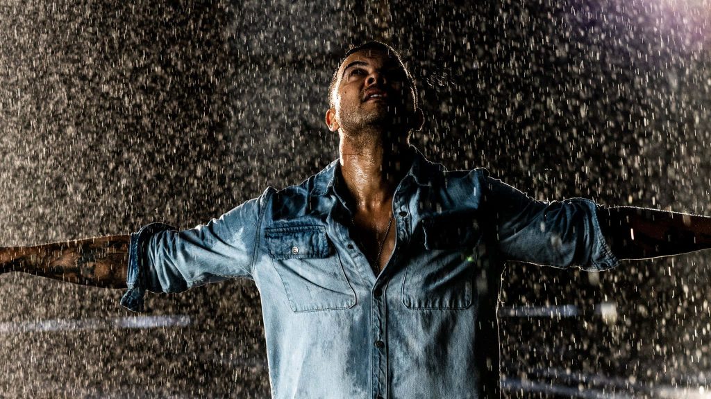 Moody Guy Sebastian rain-soaked portrait with open arms in wet denim shirt cinematic wallpaper