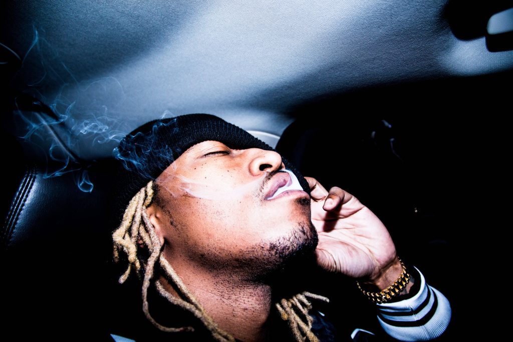 Future rapper moody high contrast wallpaper with iconic dreadlocks smoking inside car background