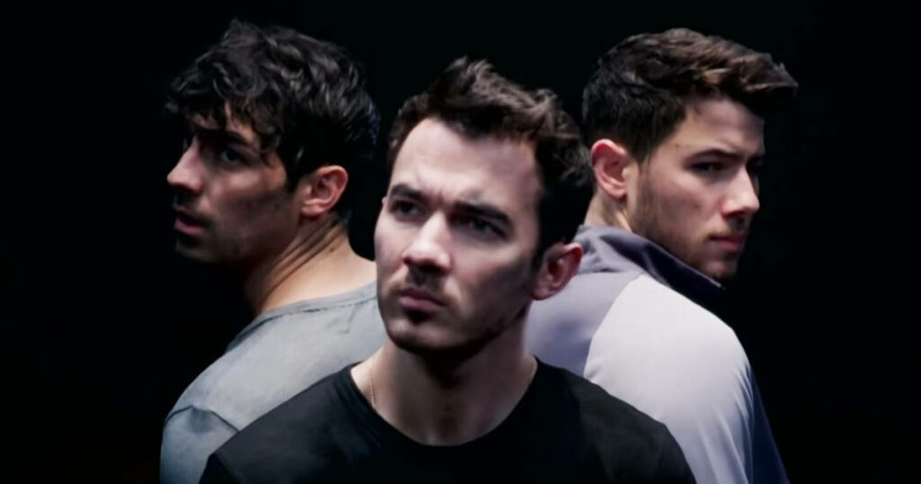 Moody Jonas Brothers Wallpaper: Intense Expressions in Dark Setting