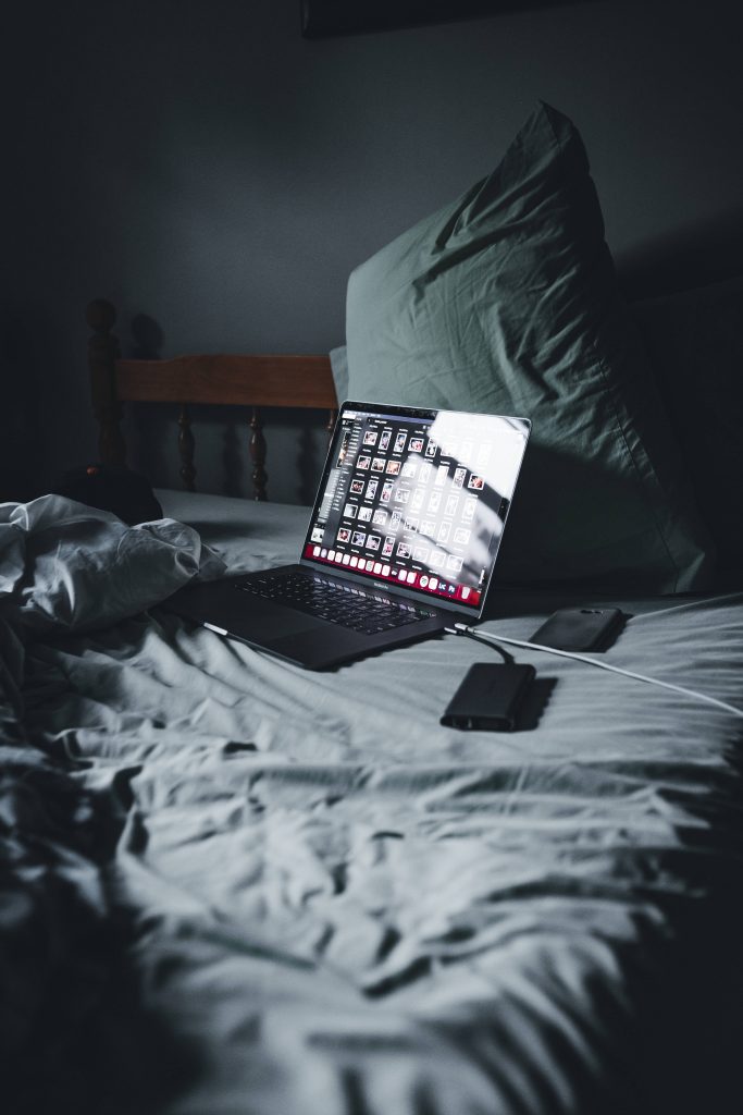 MacBook Pro late-night photo editing in dimly lit bedroom with professional software on screen Wallpaper
