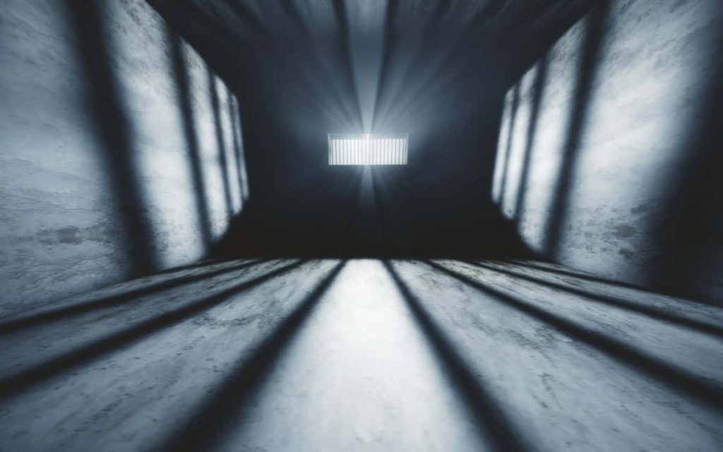 Dark concrete room with high barred window casting dramatic shadows minimalist wallpaper background