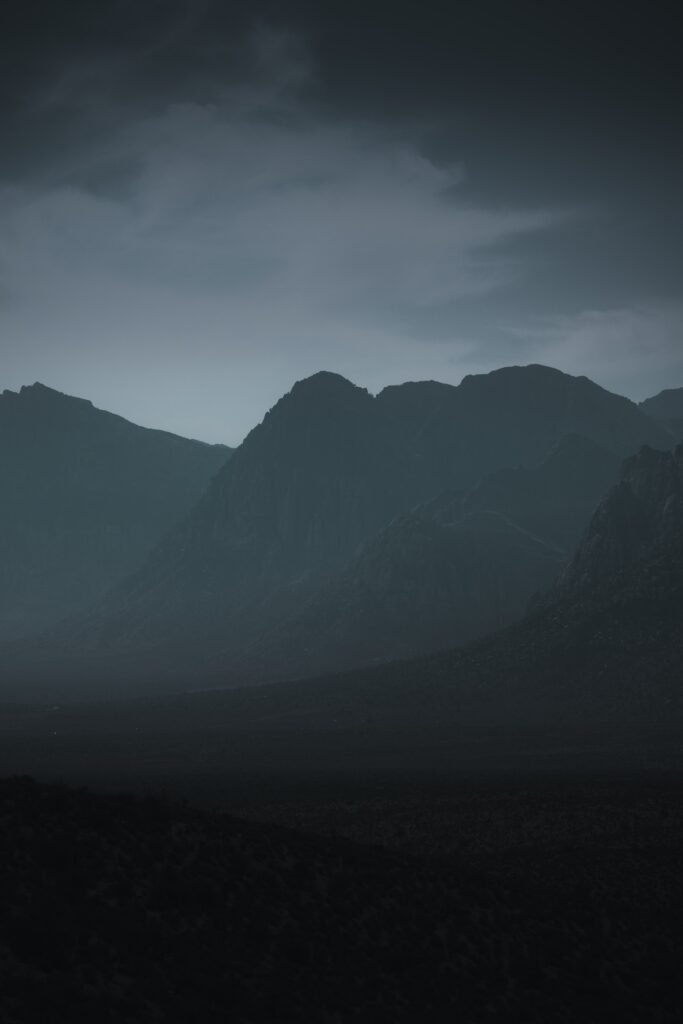 Rugged mountains in thick evening fog with deep blues and soft grays serene landscape wallpaper