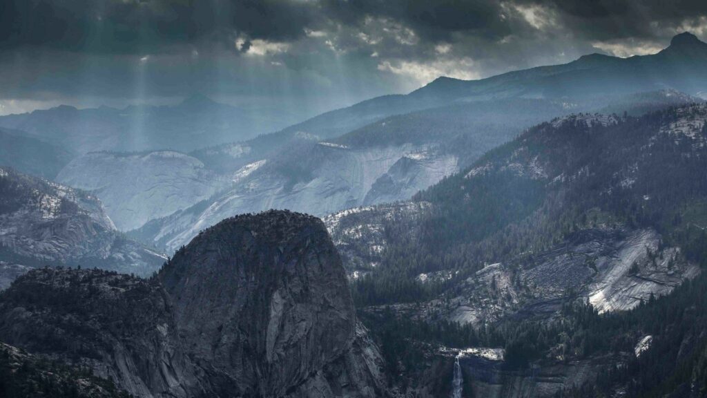 Moody mountain landscape with foggy cliffs pine ridges and soft light illuminating wild scenery Wallpaper