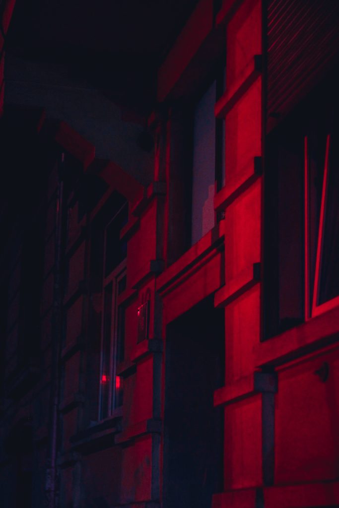 Dramatic building facade in vibrant red light with sharp shadows neon night wallpaper background
