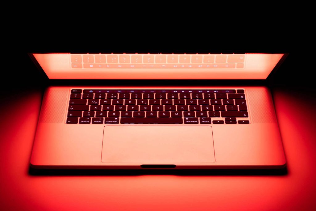 Open MacBook Pro with Turkish keyboard in intense neon red glow moody tech wallpaper