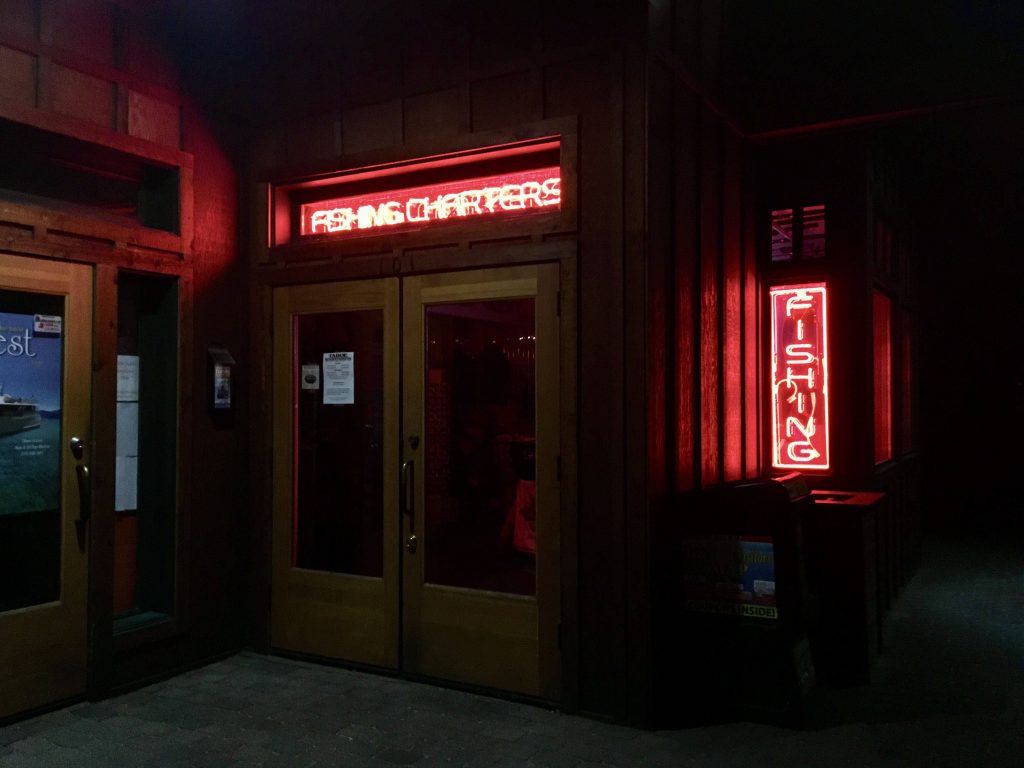 Rustic fishing charters storefront glowing red neon signs night nautical wallpaper background