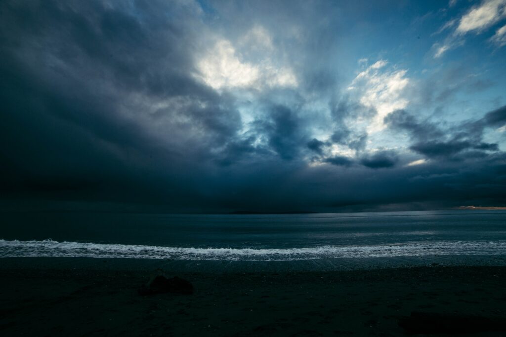 Moody night seascape wallpaper with dark overcast sky and gentle surf on quiet shore