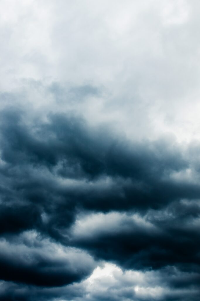 Dramatic moody sky with dark porous clouds in gray and blue high resolution wallpaper background