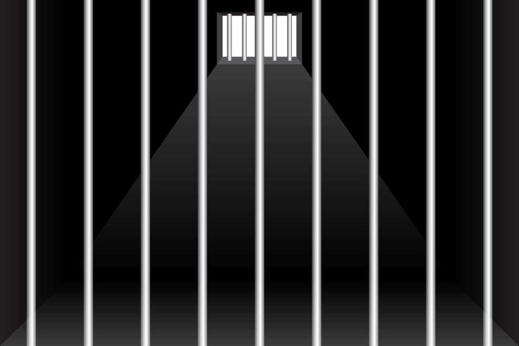 Moody prison cell interior with steel bars and light streaming through a solitary window background Wallpaper