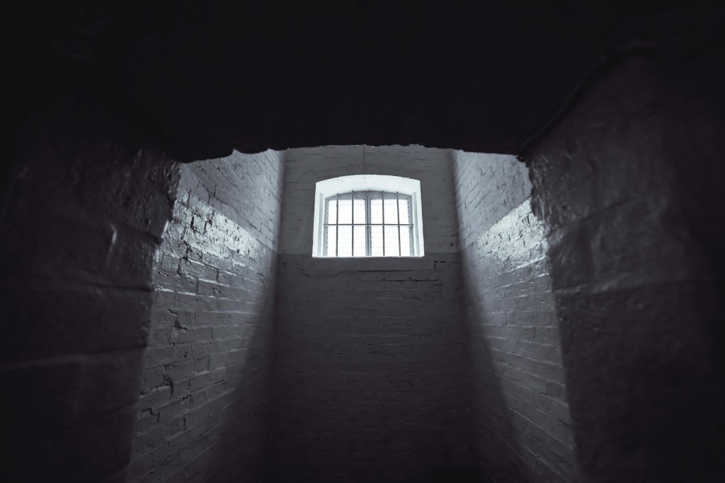 Dim prison cell wallpaper with barred window light on textured brick walls dramatic scene