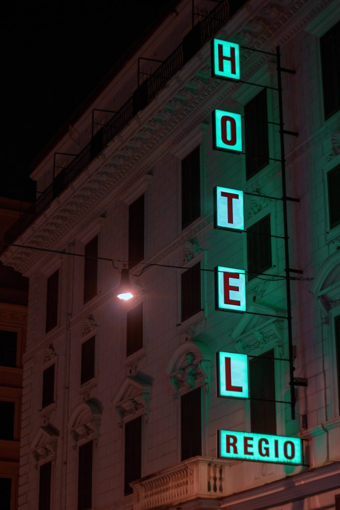 Hotel Regio neon sign glowing teal on classic Rome architecture night wallpaper background