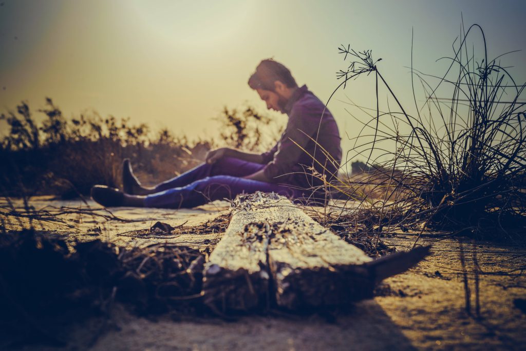 Man sitting alone at sunset in desolate landscape moody sad aesthetic wallpaper background