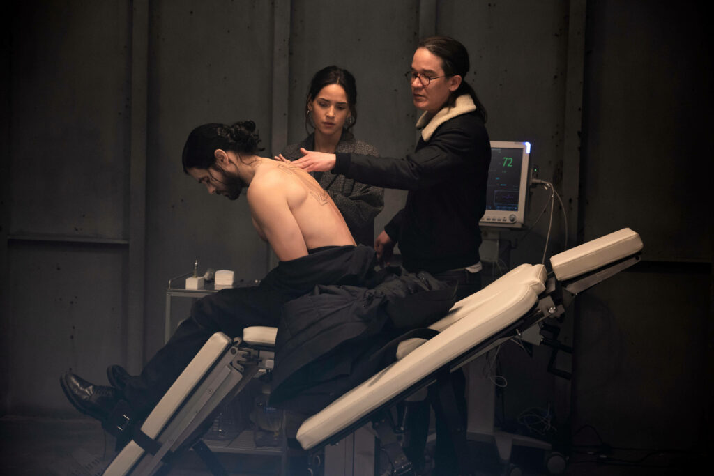 Morbius in medical chair with doctor checking back and woman observing in dramatic scene Wallpaper