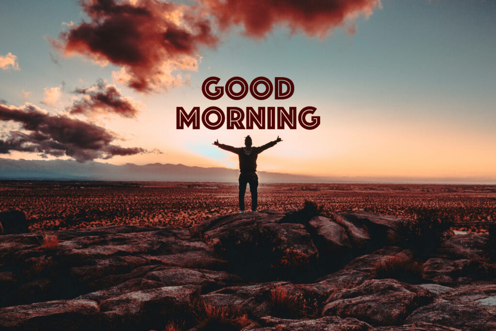 Triumphant silhouette on rocky outcrop at sunrise desert good morning motivational wallpaper background