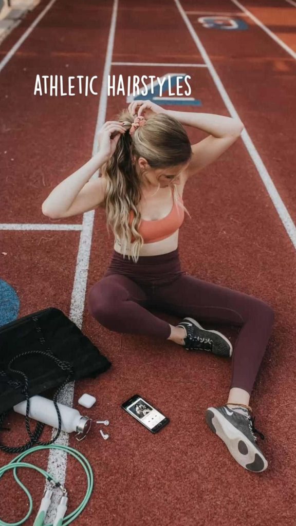 Woman in stylish activewear on running track with jump rope water bottle and phone fitness gear Wallpaper