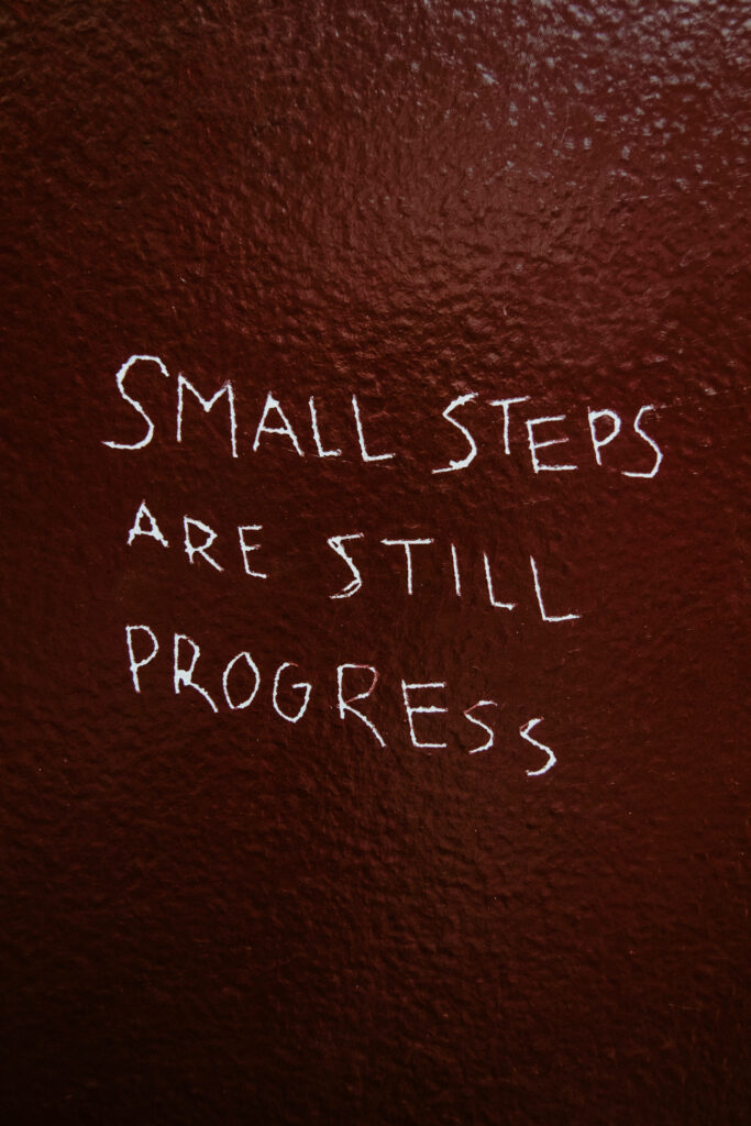 Motivational Wallpaper: 'Small Steps Are Still Progress' on Dark Red