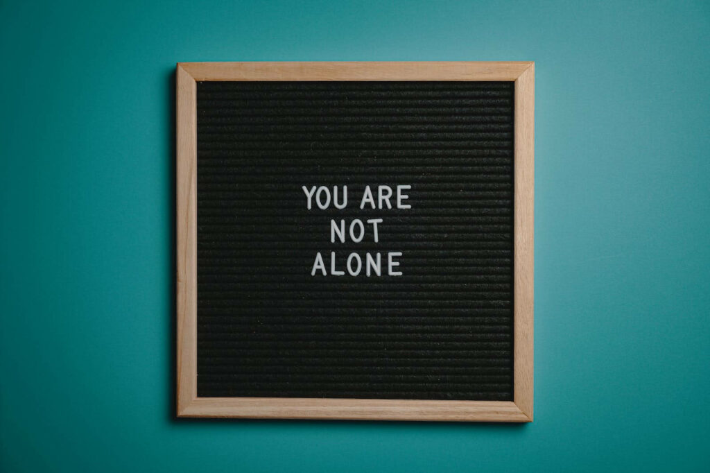 Motivational 'You Are Not Alone' Wallpaper on Teal Background