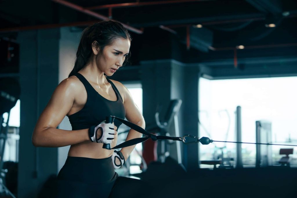 Athletic woman doing unilateral workout in moody modern gym with focused intensity and strength Wallpaper