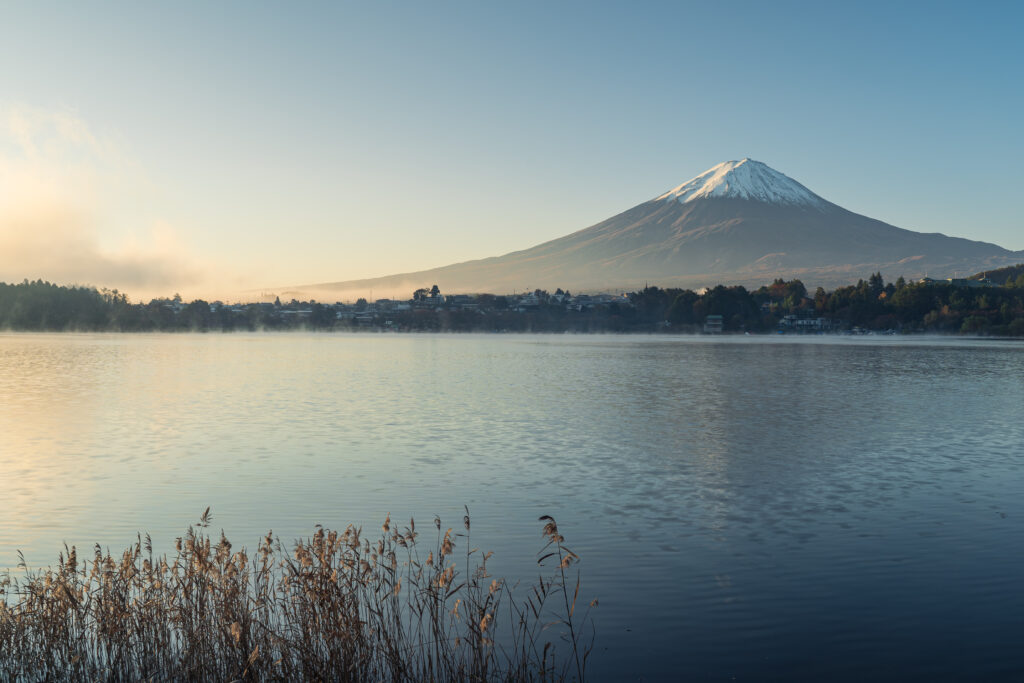 Mount Fuji reflected in calm lake with soft morning light on snow-capped peak serene wallpaper