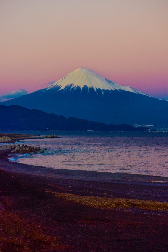 Mount Fuji at sunset above calm beach waters with pastel skies and snow-capped peak wallpaper background
