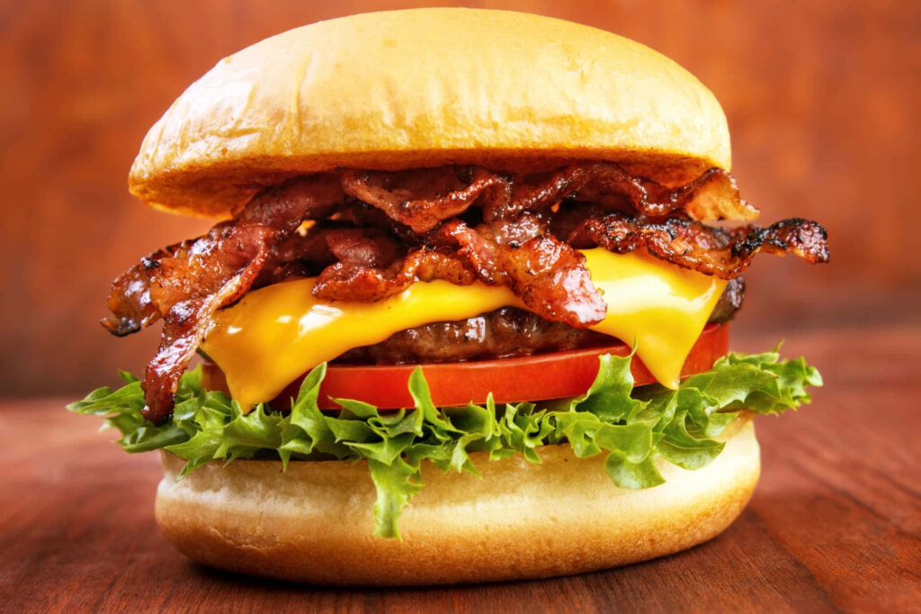Close-Up of Juicy Bacon Cheeseburger with Fresh Toppings - Wallpaper