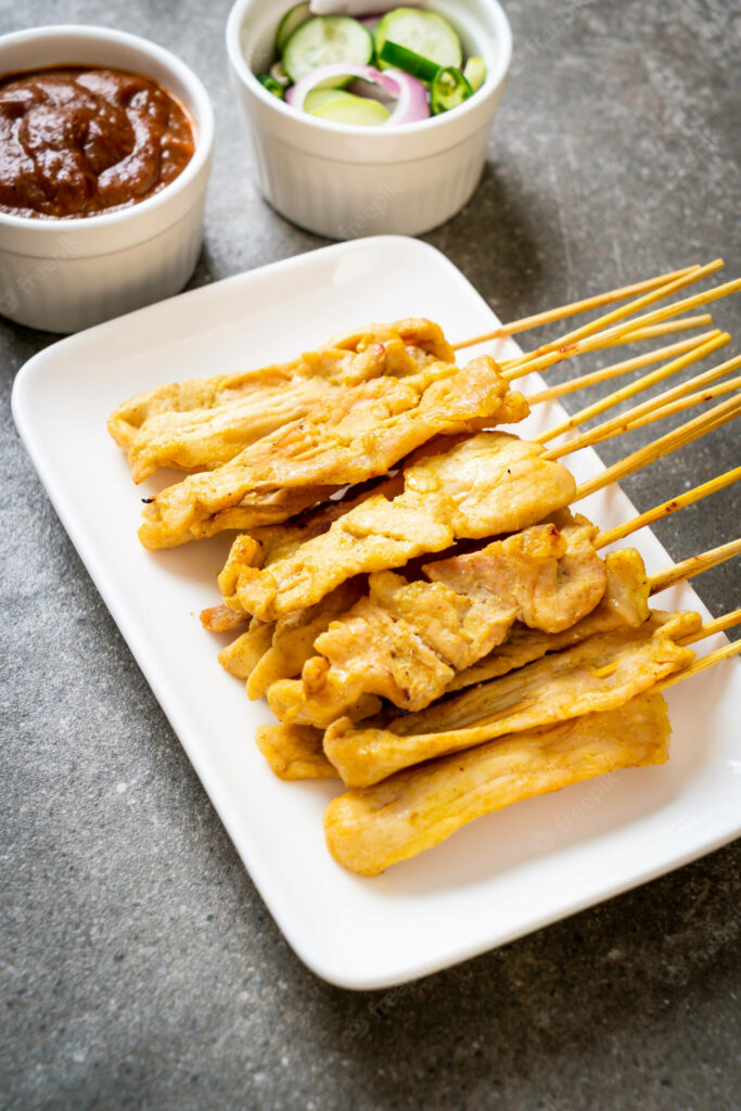 Delicious Chicken Satay Skewers Wallpaper with Peanut Sauce & Cucumbers