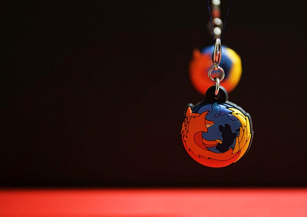 Close-up of colorful Mozilla Firefox logo keychain on dark minimalist background wallpaper