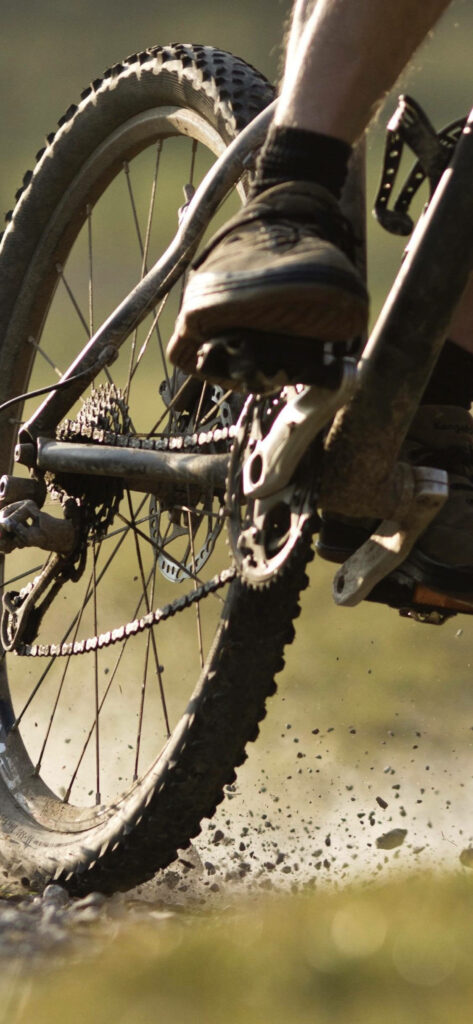 Close-up of muddy bicycle wheel in motion showcasing outdoor adventure action wallpaper background