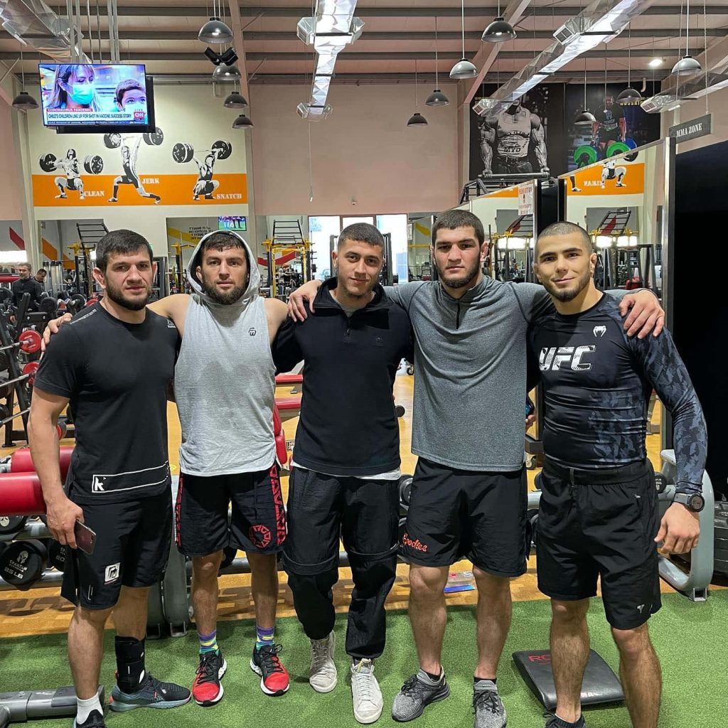 UFC fighter Muhammad Mokaev with fellow MMA athletes in realistic gym training wallpaper background