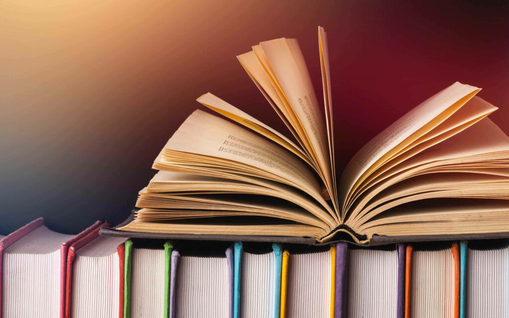 Colorful Tale: A Book Uncovered Among Multicolored Pages Wallpaper