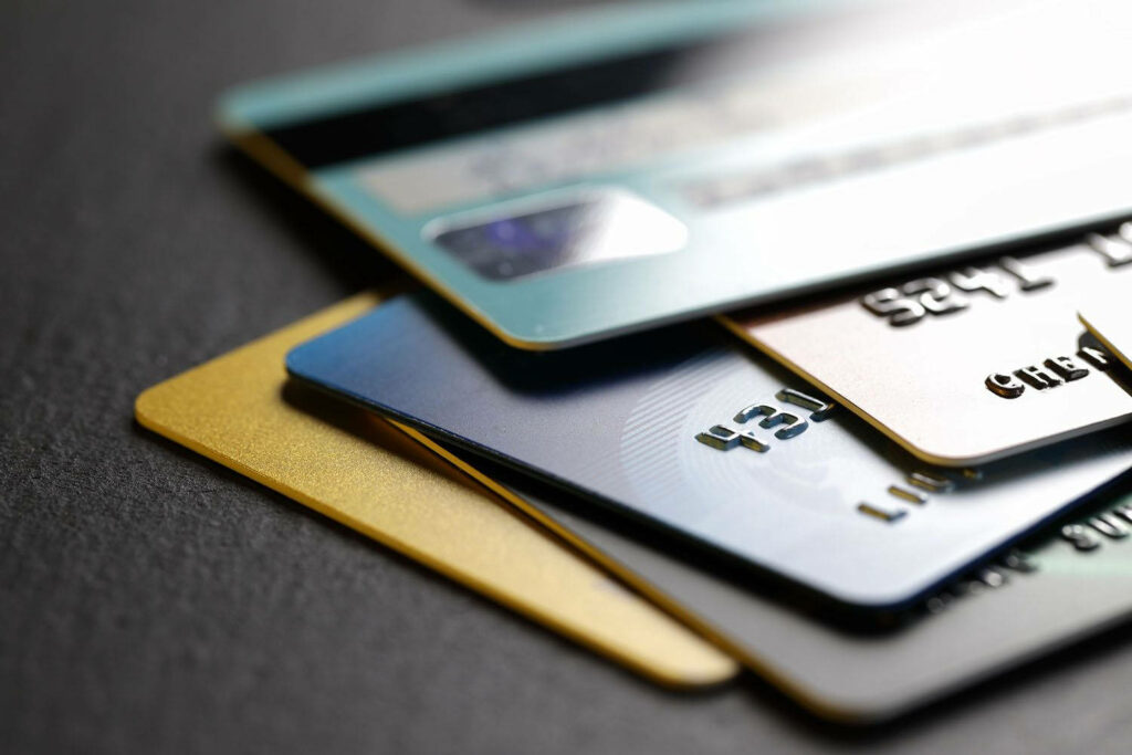 Close-up of colorful stacked credit cards showing metallic textures and embossed numbers on dark background Wallpaper