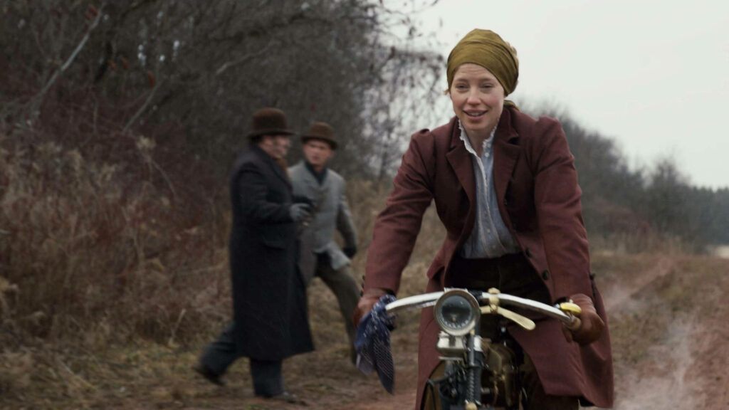 Muriel Stacy cycling on rural autumn path in period clothing showing determined spirit wallpaper