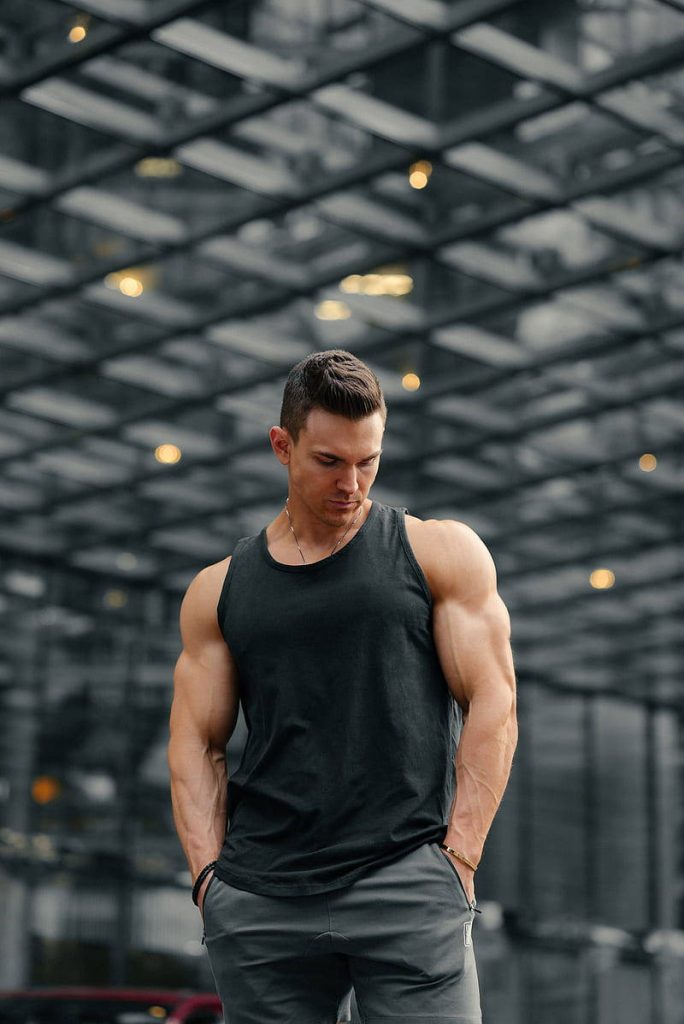 Muscular bodybuilder in black tank top posing confidently in modern urban HD wallpaper background
