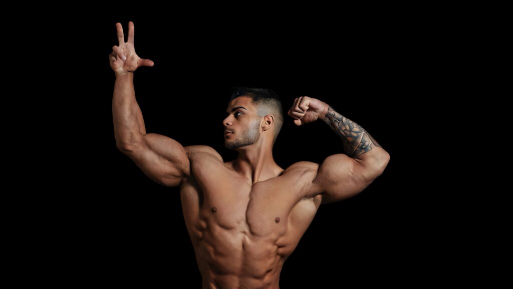 Muscular bodybuilder posing with defined abs strong arms and detailed tattoos on black background Wallpaper