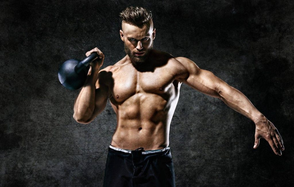 Muscular man lifting kettlebell with dramatic lighting workout wallpaper for fitness motivation